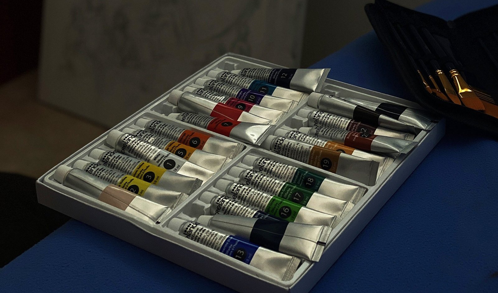 Tubes de peinture à l'huile et pinceaux dans l'atelier d'Angelina Spark, avec une toile en cours au fond